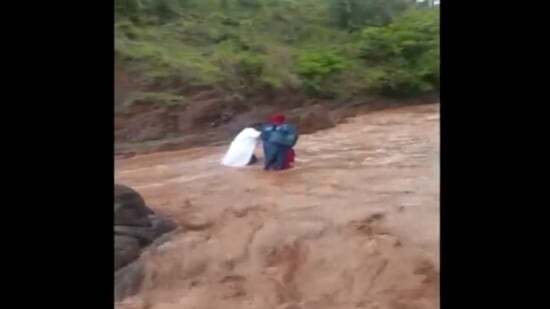 Healthcare workers crossing a river in Jammu and Kashmir for door-to-door vaccination.(Twitter/@ANI)