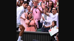 The image shows Novak Djokovic walking away after gifting his racquet to a young fan.