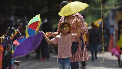 A woman and her child shop for umbrellas at Janpath amid the scorching heat in New Delhi on July 5. (HT file)
