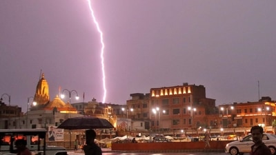 Commuters cross a road during a lightning strike in Jaipur on Sunday. (PTI Photo)