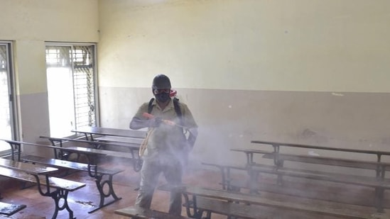 An MCD worker sprays disinfectant inside a classroom at Bengaluru's Maharani College of Arts and Science