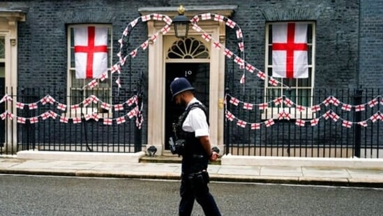 A police officer walks past 10 Downing Street decorated with England flags, in London, Monday, July 12, 2021, after Italy beat England to win the Euro 2020 soccer championship in a final played at Wembley stadium. (AP Photo/Alberto Pezzali)(AP)