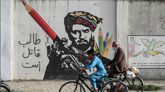 Cyclists peddle past a mural painted on the wall along a road in Kabul, Afghanistan. (Representational image/AFP)