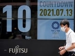 A man wearing a face mask against the spread of the coronavirus walks in front of a countdown calendar showing 10 days to start Tokyo 2020 Olympics.(AP) A man wearing a face mask against the spread of the coronavirus walks in front of a countdown calendar showing 10 days to start Tokyo 2020 Olympics.(AP)