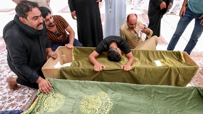 Mourners react next to the coffins of a victim, who was killed in a fire that broke out at al-Hussain coronavirus hospital in Nassiriya, during a funeral in Najaf, Iraq, July 13, 2021. (REUTERS)