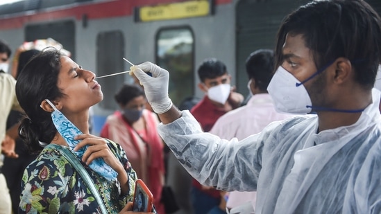 A BMC worker collects sample of a passenger for Covid-19 test, at a train station in Mumbai on Sunday.(PTI Photo)