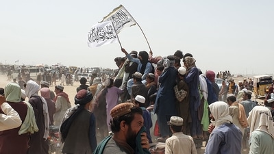 People wave Taliban flags as they drive through the Pakistani border town of Chaman on July 14, 2021. (AFP) People wave Taliban flags as they drive through the Pakistani border town of Chaman on July 14, 2021. (AFP)