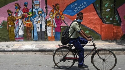 A cyclist passes by a wall mural depicting frontline Covid-19 coronavirus workers, in New Delhi. (File photo / AFP) A cyclist passes by a wall mural depicting frontline Covid-19 coronavirus workers, in New Delhi. (File photo / AFP)
