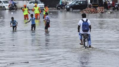 Commuters wade through a waterlogged road after heavy rain in Patiala on Wednesday, July 14. (PTI)