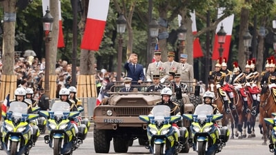 French President Emmanuel Macron and French Armies Chief of Staff General Francois Lecointre stand in the command car as they review the troops during the annual Bastille Day military parade on the Champs-Elysees avenue in Paris.  (Photo by Ludovic MARIN/POOL / AFP)