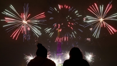 People watch the fireworks explode above the Eiffel Tower as part of the celebrations in Paris.  (Photo by GEOFFROY VAN DER HASSELT/AFP)