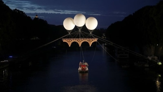 A view of an art installation by French artist Olivier Grossetete titled "The Farnese Bridge", showing a Michelangelo-inspired cardboard bridge floating above the Tiber river, suspended by three balloons, in Rome, Italy. (REUTERS/Yara Nardi)
