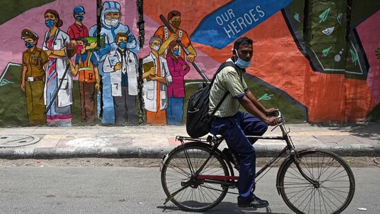 A cyclist passes by a wall mural depicting frontline Covid-19 coronavirus workers, in New Delhi. (File photo / AFP)