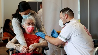 An elderly woman receives a booster shot of her vaccination against Covid-19 at an assisted living facility, in Netanya, Israel. (Reuters)