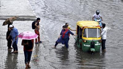 Passengers get out of an auto rickshaw that broke down on a waterlogged stretch during heavy rain near Vinod Nagar in New Delhi on Wednesday, July 14. (Ajay Aggarwal /HT photo)