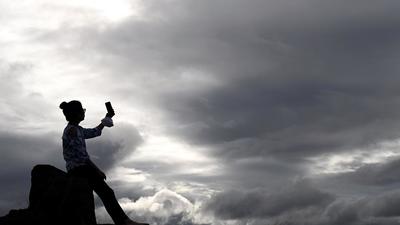 A girl taking a picture on a mobile in cloudy weather on a hill at Baner in Pune, on July 15, 2021. Truant monsoon leaves Pune with deficient rainfall in July. (KALPESH NUKTE/HT)