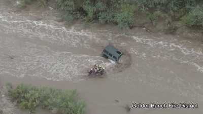 Firefighters rescue a man and two young girls who were stranded after their vehicle was washed away in flash floods near Tucson, Arizona, US, July 14, 2021, (via REUTERS)