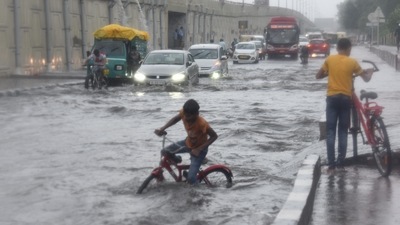 Commuters crossing a waterlogged stretch along NH24 near Mayur Vihar during heavy rain in New Delhi. (Raj K Raj / Hindustan Times)