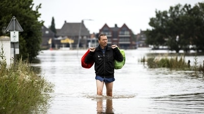 A man leaves a flooded house in Arcen on July 17 following heavy rains and floods in the in North Limburg, Netherlands. In some affected areas, firefighters, local officials and soldiers, some driving tanks, have begun the colossal work of clearing the piles of debris clogging the streets. (Remko de Waal / ANP / AFP)