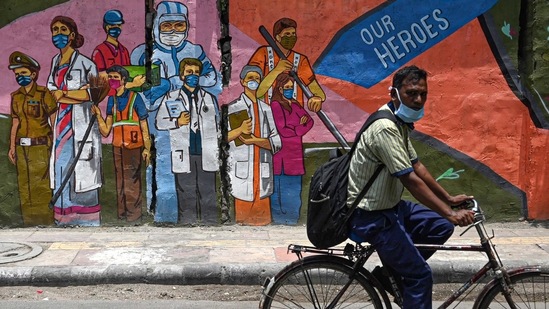 A cyclist passes by a wall mural depicting frontline workers, in New Delhi (AFP file photo)