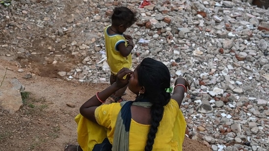 A woman with a child sit near the debris of houses after local authorities razed a settlement that was said to be in a forest land in Khori village at Faridabad district. (AFP)