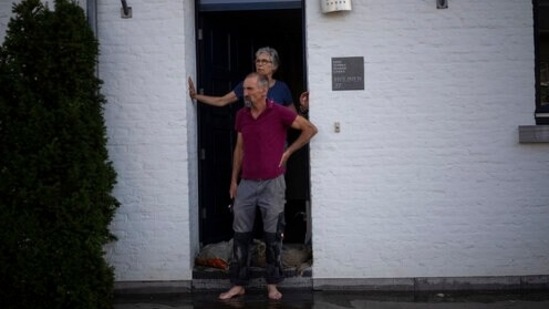 A coupe stands outside their home in Brommelen, Netherlands. "Floods always happen, and they are like random events, like rolling the dice. But we've changed the odds on rolling the dice," said Ralf Toumi, a climate scientist at Imperial College London.(AP Photo/Bram Janssen)