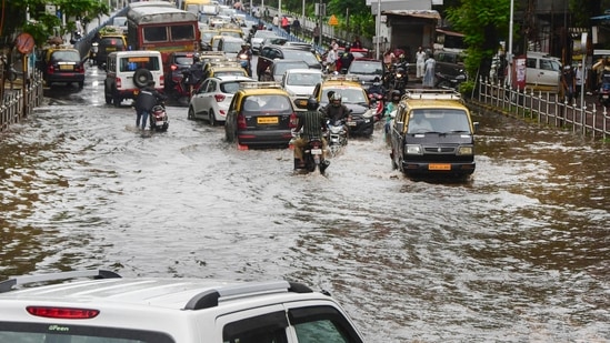 Commuters wade through a waterlogged road at Dadar after a monster thunderstorm caused heavy rains in Mumbai and adjoining areas on Sunday.(PTI)