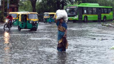A woman carries a sack while walking through a waterlogged road in New Delhi on Monday, July 19. (ANI) A woman carries a sack while walking through a waterlogged road in New Delhi on Monday, July 19. (ANI)