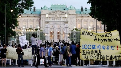 Protesters against the Tokyo Olympics gather outside Akasaka Palace, a Japanese state guest house where the welcome party for IOC President Thomas Bach and its officials are held in Tokyo on July 18, 2021. The yellow banner reads that IOC is a plunderer. (Koji Harada / Kyodo News via AP) Protesters against the Tokyo Olympics gather outside Akasaka Palace, a Japanese state guest house where the welcome party for IOC President Thomas Bach and its officials are held in Tokyo on July 18, 2021. The yellow banner reads that IOC is a plunderer. (Koji Harada / Kyodo News via AP)