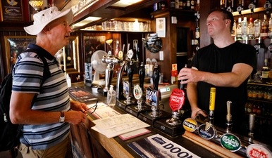 A customer drinks a drink standing at the bar of a pub in central London on July 19, 2021 as coronavirus restrictions are lifted. (AFP)
