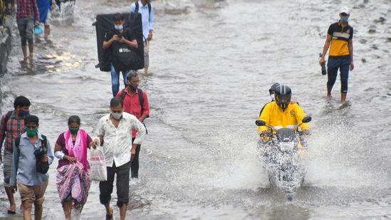 Commuters travel through a waterlogged road after heavy rainfall, at Matunga, in Mumbai on Sunday. (ANI Photo)
