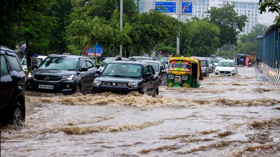 Vehicles wade through a waterlogged street after heavy rains near Medicity Hospital in Gurugram on Monday, July 19. (PTI)