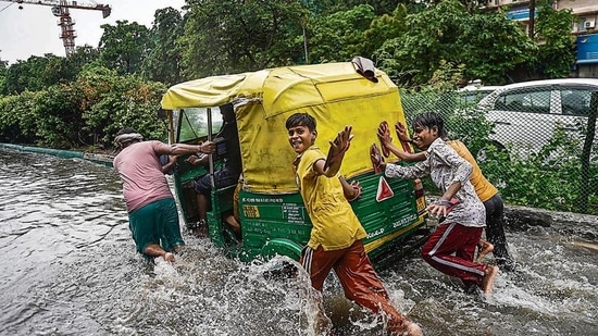 People push an autorickshaw through a waterlogged street following heavy rains, near ITO in New Delhi. (PTI Photo)