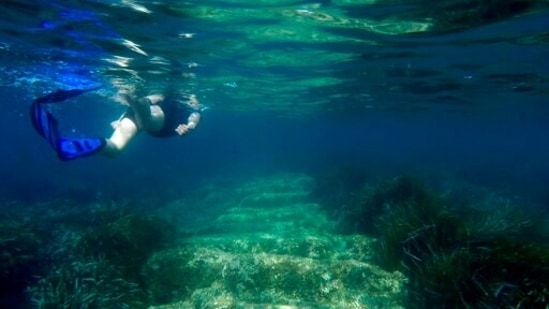 Cyprus Antiquities Department official Yiannis Violaris snorkels over submerged stone remains of the ancient harbor next of Amathus ancient city, in the eastern Mediterranean island of Cyprus, on Thursday, July 1, 2021. Lying just a few feet underwater a mere 200 feet off the coastline near the resort town of Limassol, this 2,400 year-old harbor said to be built Alexander the Great's successors will soon be Cyprus' newest tourist attraction where adventurous holidaymakers could snorkel over its submerged stone remains.(AP Photo/Petros Karadjias)