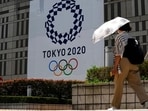 A woman wearing a protective mask walks with an umbrella to shield from the sun walks in front of a Tokyo 2020 display at Tokyo Metropolitan government building at the 2020 Summer Olympics, Tuesday, July 20, 2021, in Tokyo(AP)