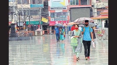 People walk on a road in Mandi amid rain on Tuesday. The red alert has been issued for Mandi, Shimla, Kangra, Kullu and Chamba districts. (Birbal Sharma/HT)