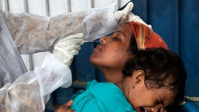 A health worker collects a swab sample of a traveler to test for Covid-19 at a train station in Mumbai, India. (AP)