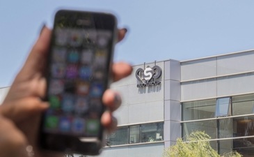 A woman uses her iPhone in front of the building housing the Israeli NSO group "Pegasus", in Herzliya, near Tel Aviv. (AFP)