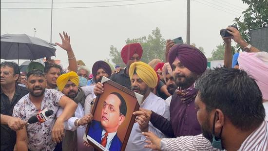 The rain was no deterrent as newly appointed Punjab Congress chief Navjot Singh Sidhu and Kuljit Singh Nagra, one of the four working presidents, hold up a portrait of Dalit leader Dr BR Ambedkar after visiting the museum at Bhagat Singh’s native village of Khatkar Kalan on Tuesday. (HT Photo)