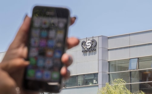 A woman uses her iPhone in front of the building housing the Israeli NSO group "Pegasus", in Herzliya, near Tel Aviv.(AFP)