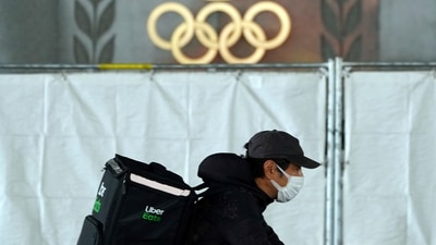 An Uber Eats delivery person carries items near the Japan National Stadium, where opening ceremony and other events are planned for postponed Tokyo 2020 Olympics (AP) An Uber Eats delivery person carries items near the Japan National Stadium, where opening ceremony and other events are planned for postponed Tokyo 2020 Olympics (AP)