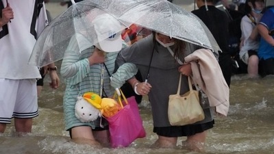 Residents, holding umbrellas amid heavy rainfall, wade through floodwaters on a road in Zhengzhou, Henan province, China via REUTERS  (VIA REUTERS)