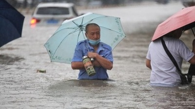 Residents wade through floodwaters on a flooded road amid heavy rainfall in Zhengzhou, Henan province, China via REUTERS (VIA REUTERS)