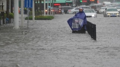 A resident wearing a rain cover stands on a flooded road in Zhengzhou, Henan province, China via REUTERS  (VIA REUTERS)