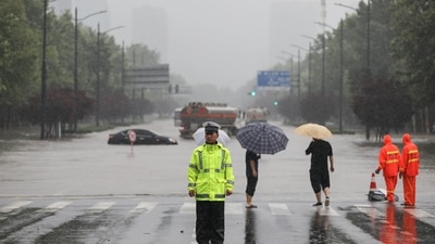 Police officer standing guard in front of a flooded street following heavy rains in Zhengzhou in China's central Henan province. (AFP) Police officer standing guard in front of a flooded street following heavy rains in Zhengzhou in China's central Henan province. (AFP)
