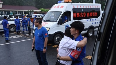 Two members of rescue organization Bluesky rescue team hug before heading to Zhengzhou, a flood-hit city in central China, in Beijing on July 21, 2021. (Photo by JADE GAO / AFP) (AFP) Two members of rescue organization Bluesky rescue team hug before heading to Zhengzhou, a flood-hit city in central China, in Beijing on July 21, 2021. (Photo by JADE GAO / AFP) (AFP)