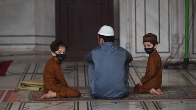 A man sits with his children after offering prayers during the Eid al-Adha festival, the feast of sacrifice at Jama Masjid. (Money Sharma/AFP) A man sits with his children after offering prayers during the Eid al-Adha festival, the feast of sacrifice at Jama Masjid. (Money Sharma/AFP)
