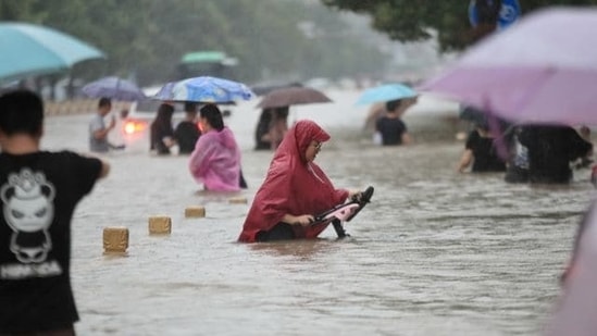 Residents wade through floodwaters on a flooded road amid heavy rainfall in Zhengzhou, Henan province, China via REUTERS (VIA REUTERS)