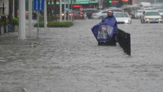 A resident wearing a rain cover stands on a flooded road in Zhengzhou, Henan province, China via REUTERS (VIA REUTERS)