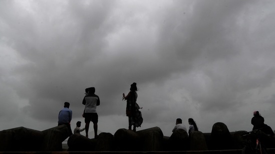 People sit by the sea shore in Mumbai.(AP) People sit by the sea shore in Mumbai.(AP)